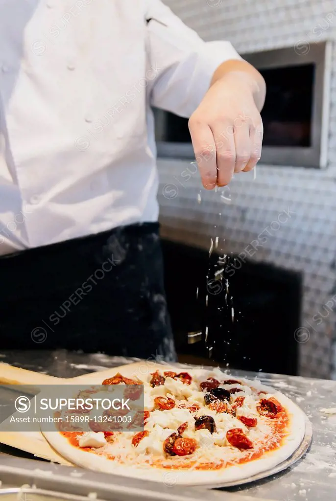 Chef making pizza in restaurant in kitchen