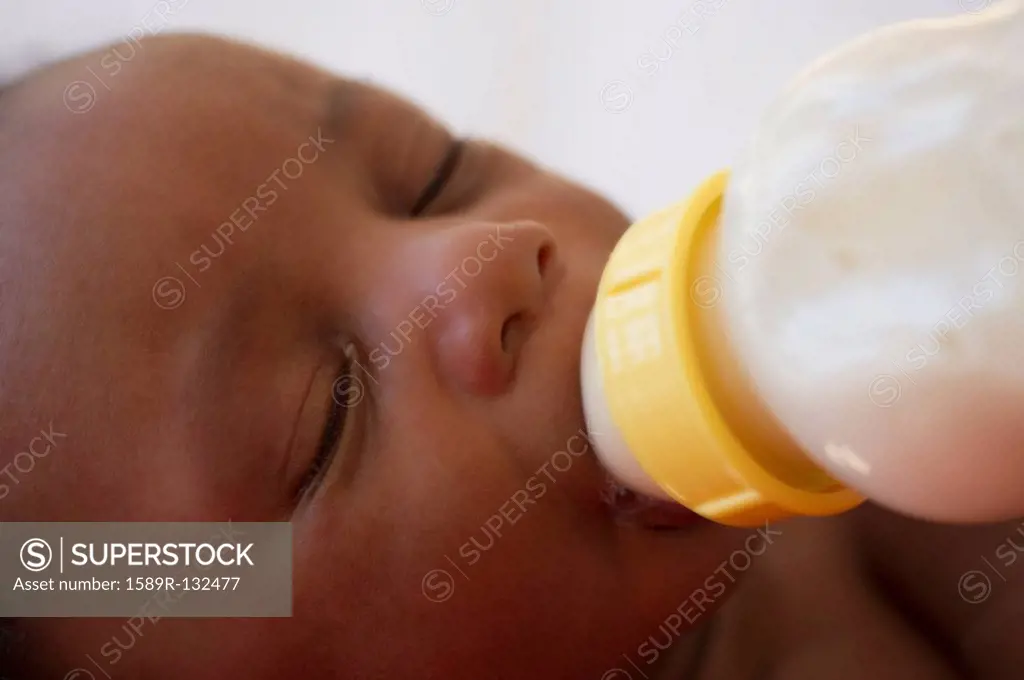 Newborn Black baby drinking from bottle