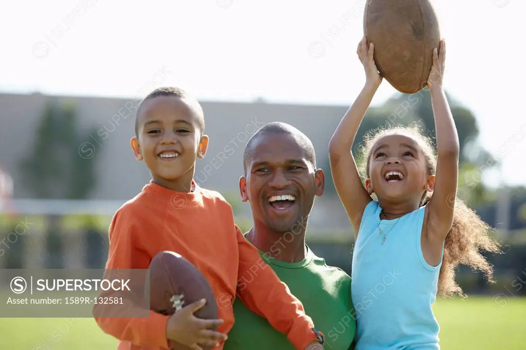 African American father, son and daughter playing football