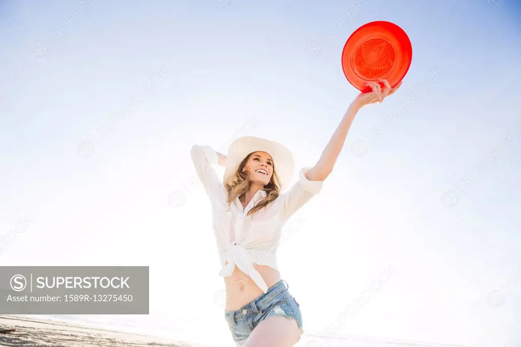Caucasian woman holding plastic disc on beach
