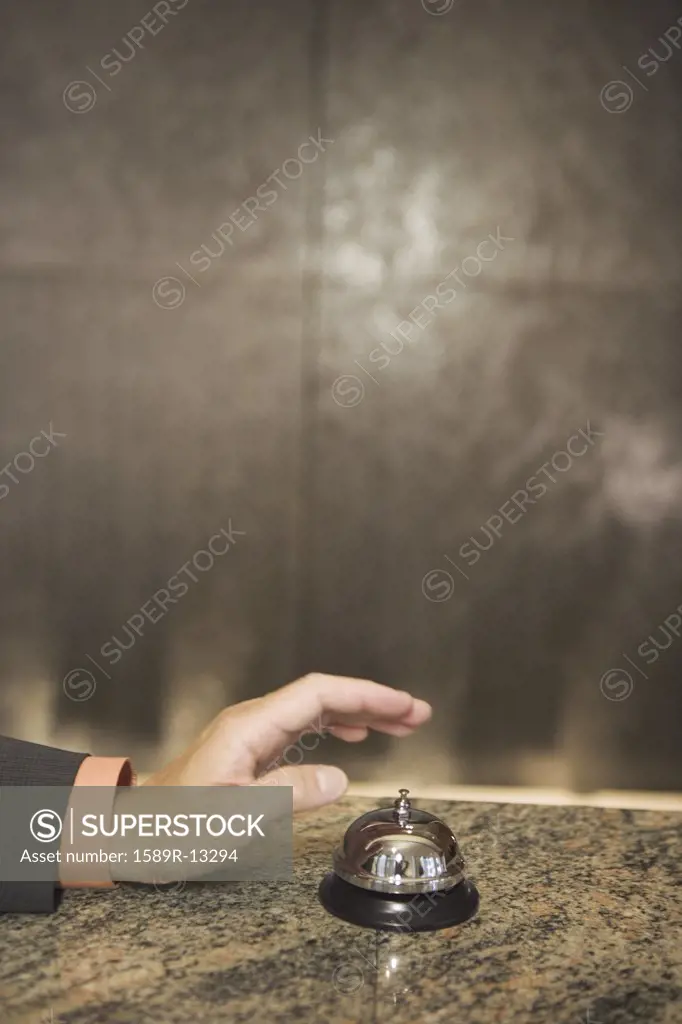 Hand reaching for service bell on counter