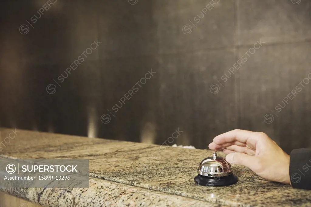 Hand reaching for service bell on counter