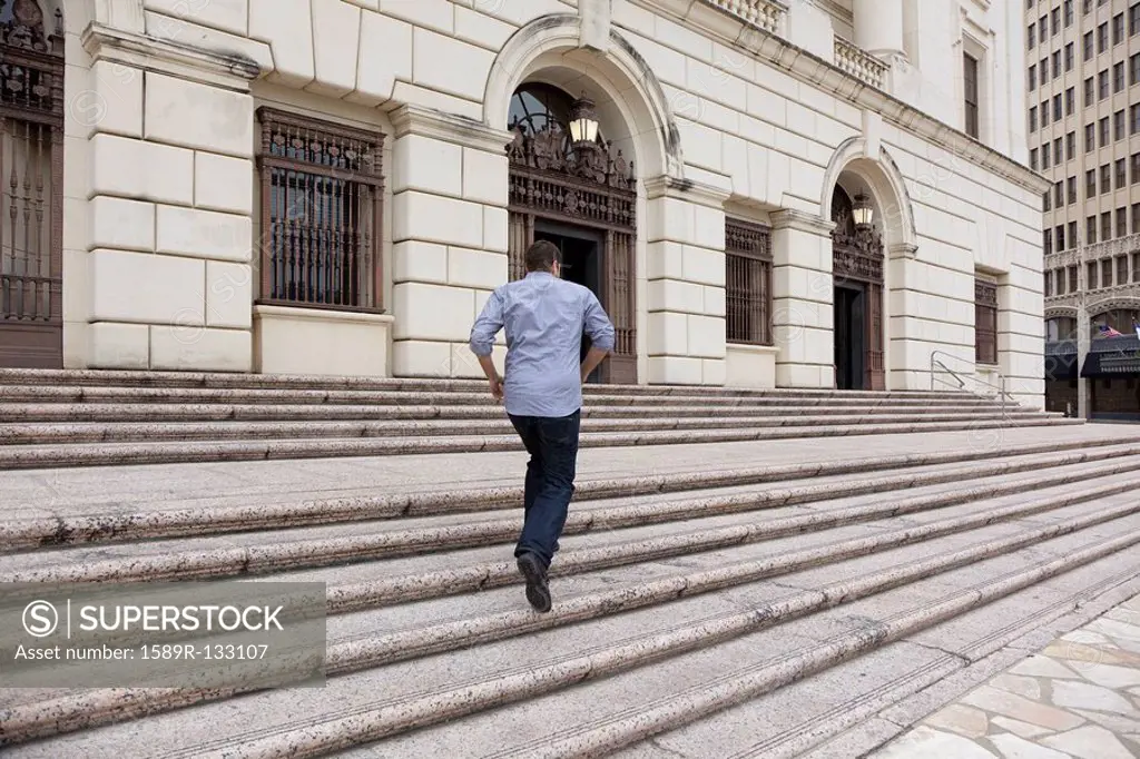 Hispanic man running up steps of urban building