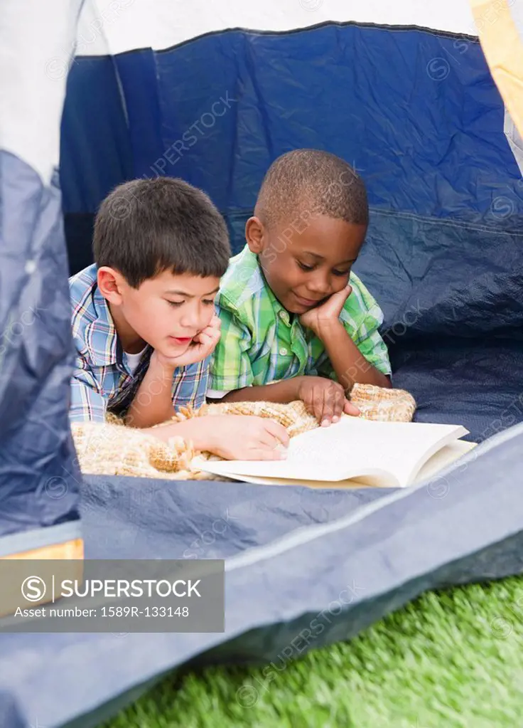 Boys reading book in tent