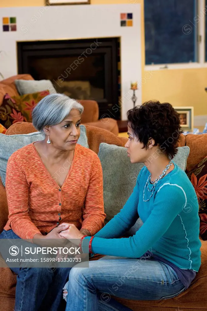 African American mother talking with daughter in living room