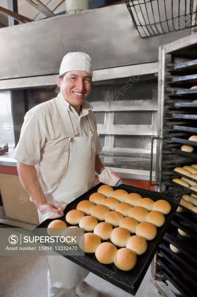 Hispanic baker holding tray with bread