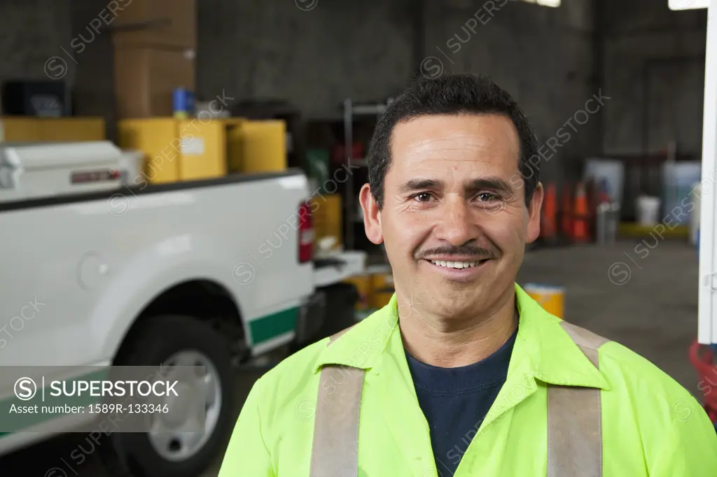 Hispanic sanitation worker smiling in garage