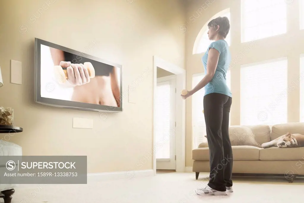 Mixed race woman watching exercise program on television