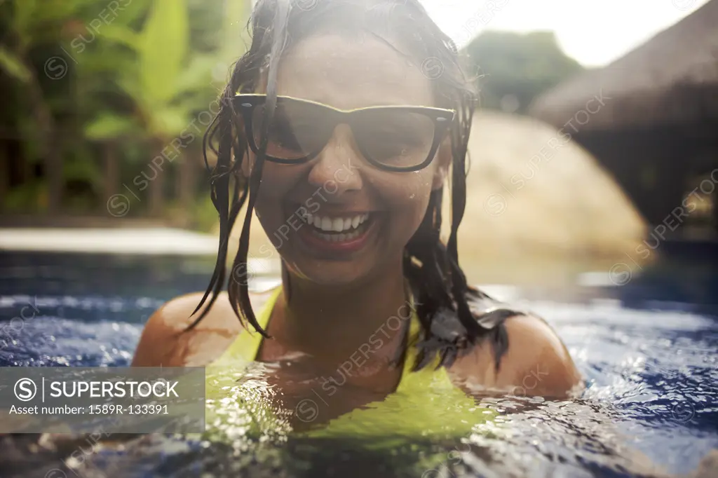 Mixed race woman wearing sunglasses in swimming pool