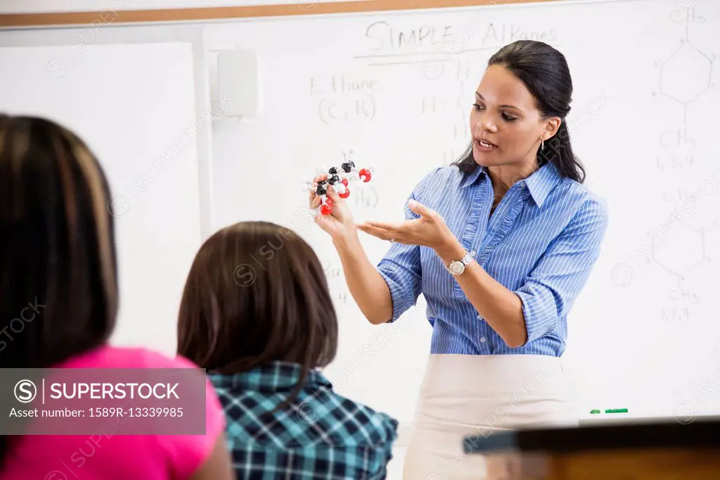 Black teacher showing students chemistry model