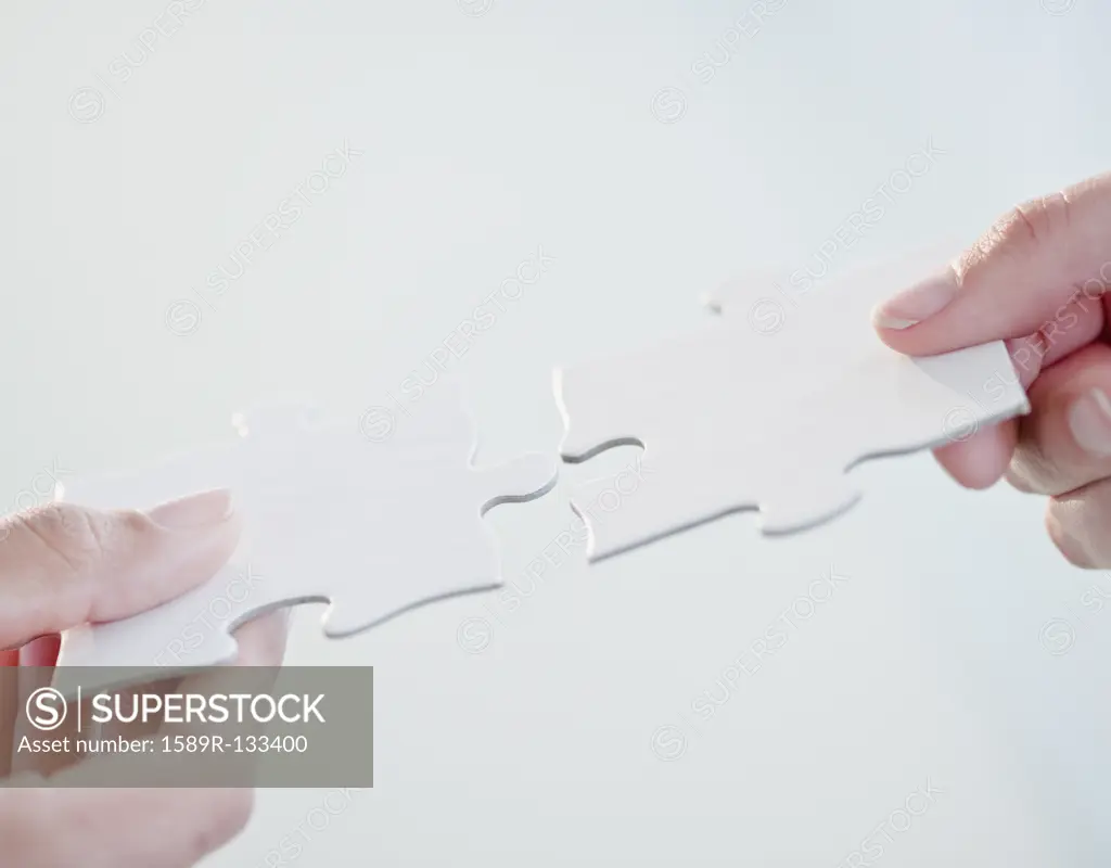 Hands connecting jigsaw puzzle pieces