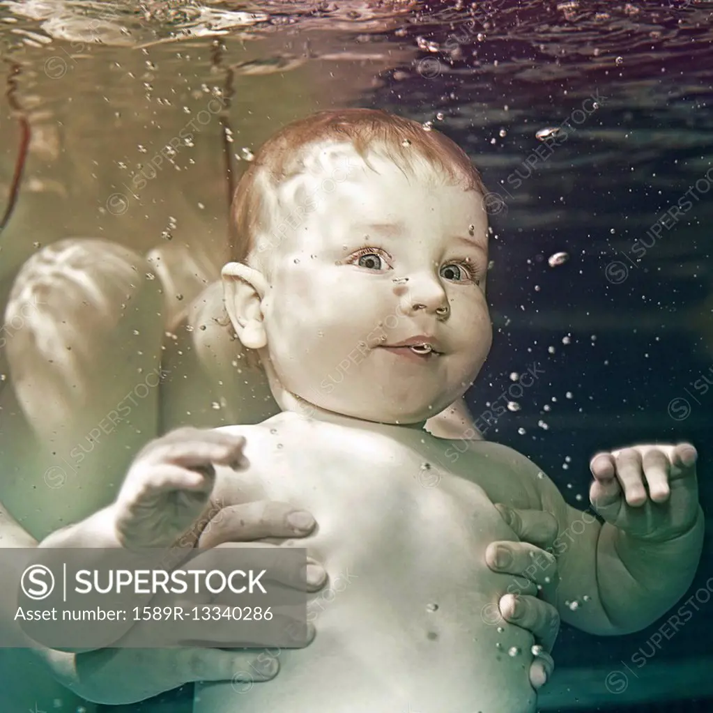 Caucasian baby being held underwater