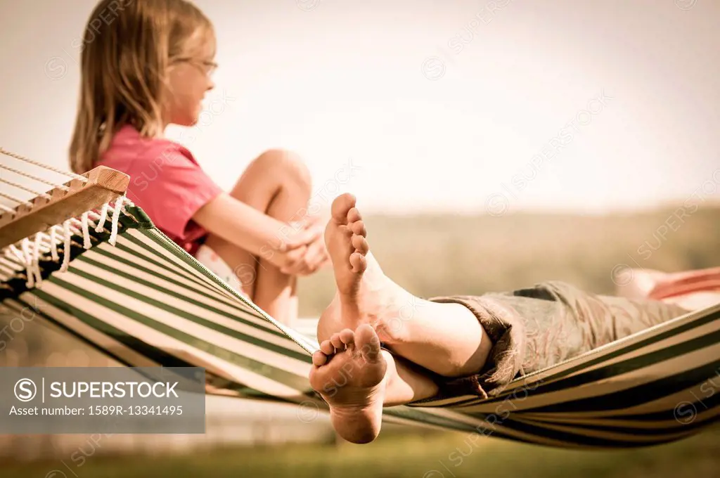 Mother and daughter relaxing in hammock outdoors