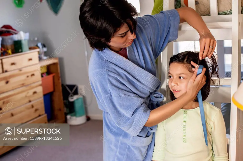 Hispanic mother brushing daughter's hair