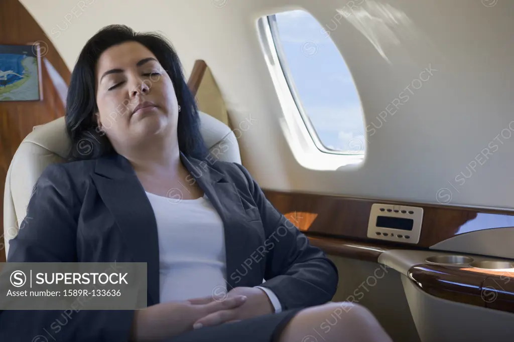 Hispanic businesswoman sleeping on private jet