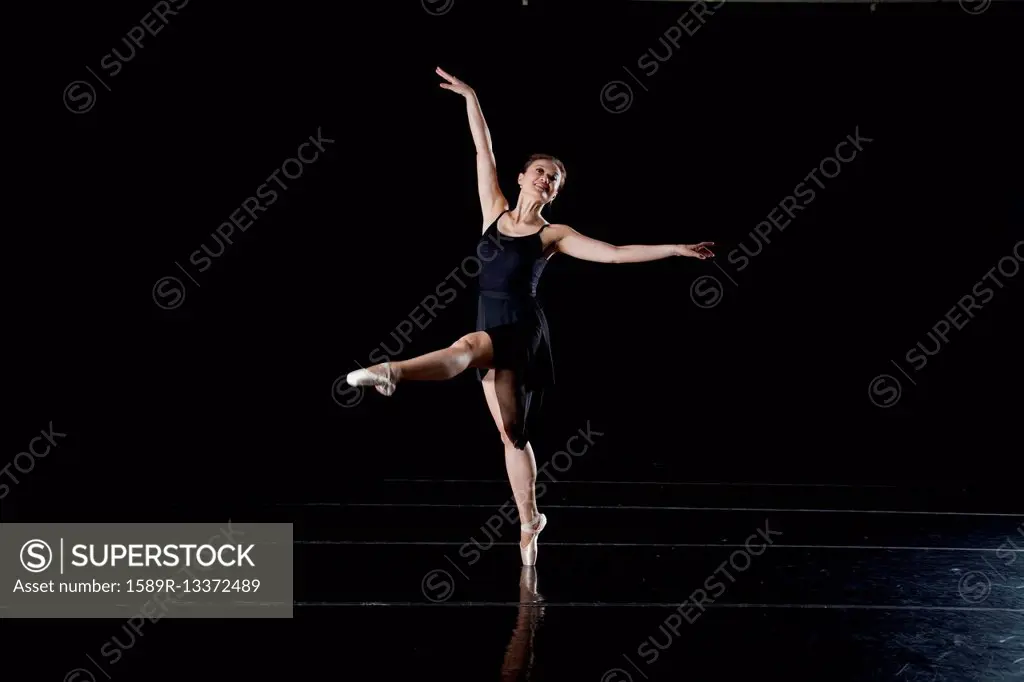 Asian ballerina dancing on dark stage