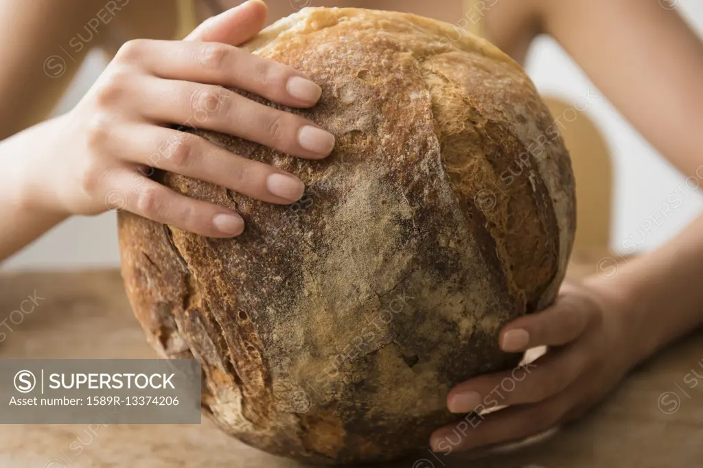 Hispanic woman holding round loaf of bread