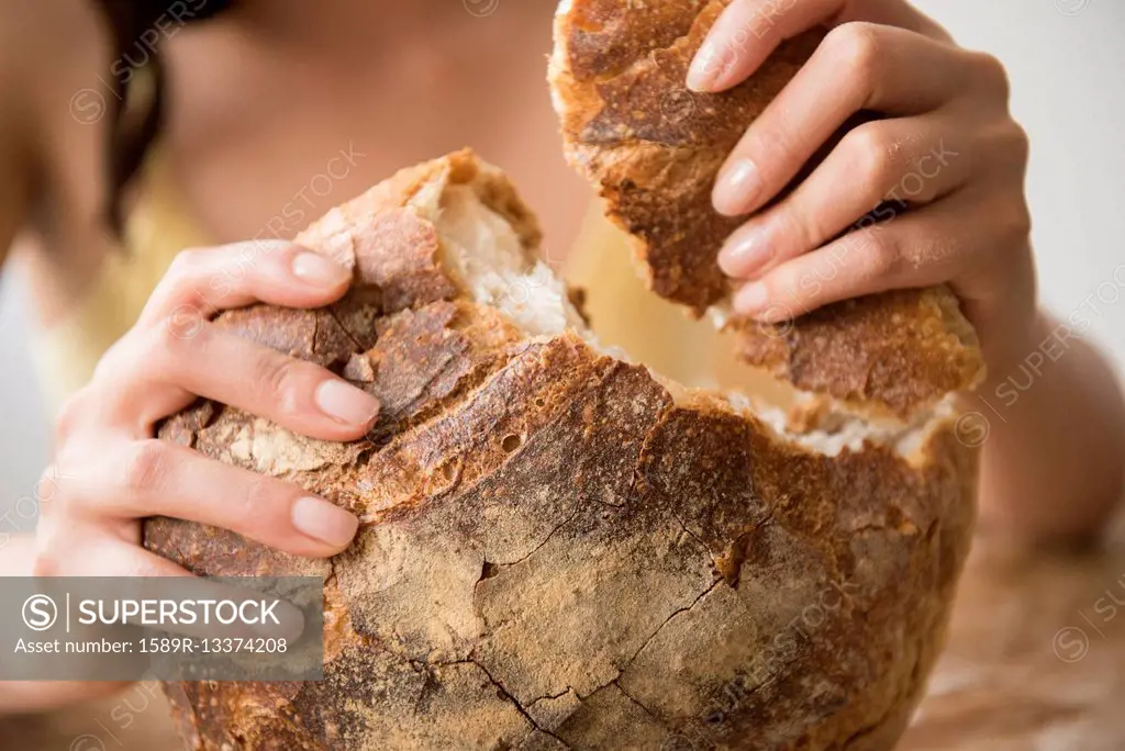 Hispanic woman tearing round loaf of bread