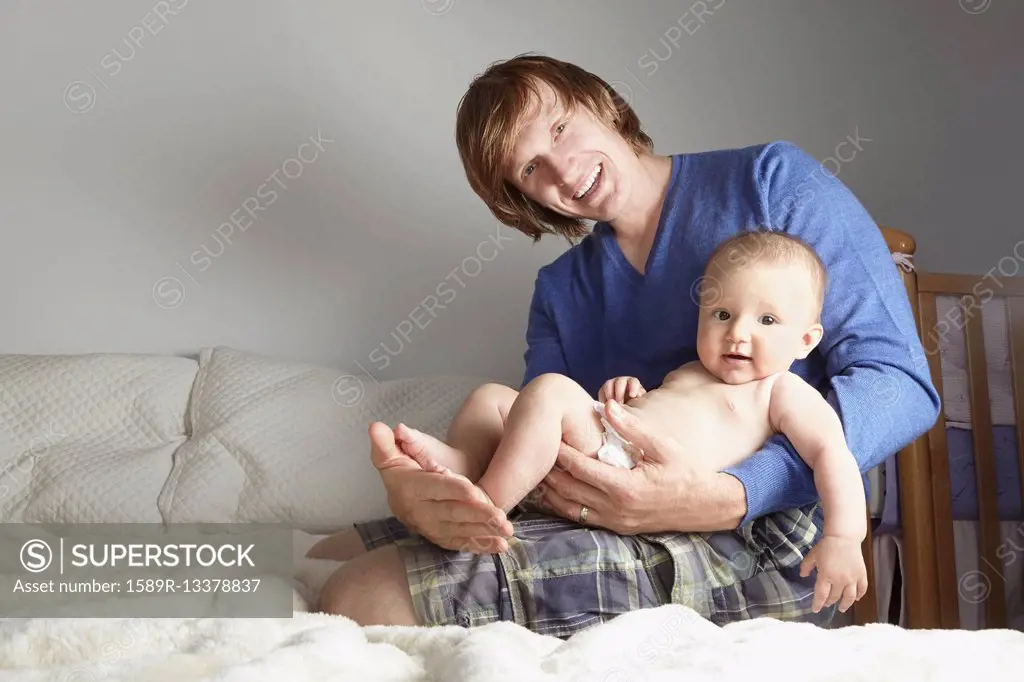 Father holding baby on bed