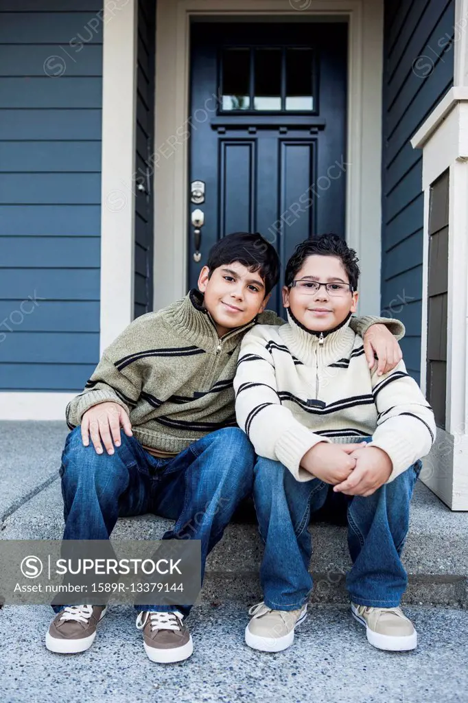 Hispanic boys hugging on front stoop