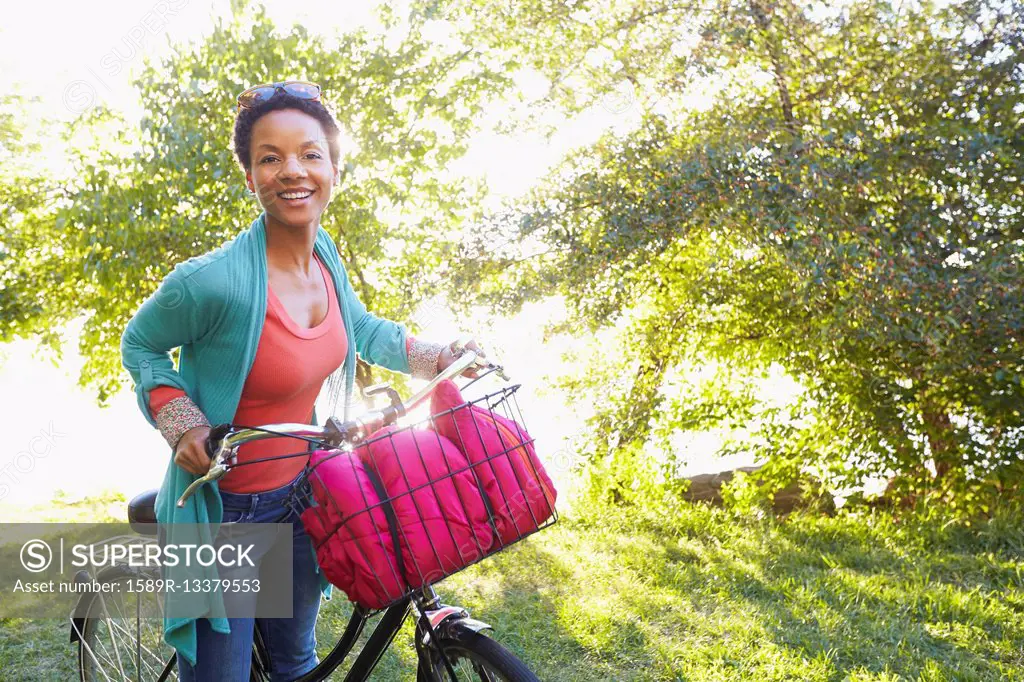 Black woman pushing bicycle outdoors