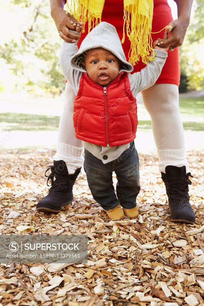 Black mother and toddler son playing in park
