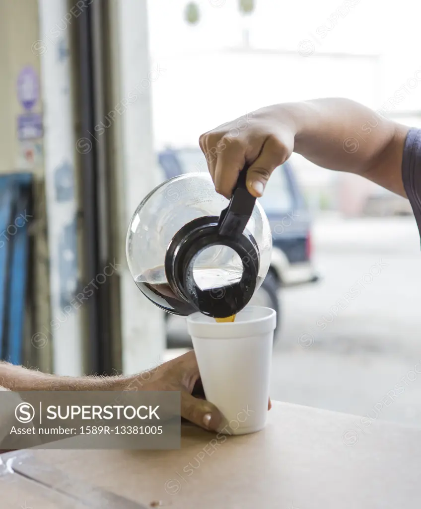 Workers pouring cup of coffee in warehouse