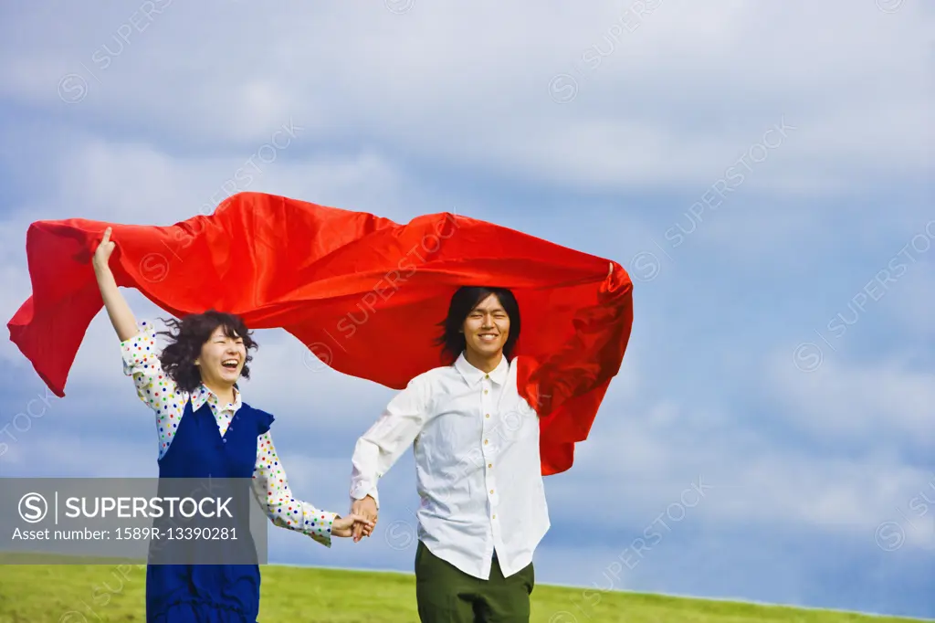 Asian couple holding blanket in wind