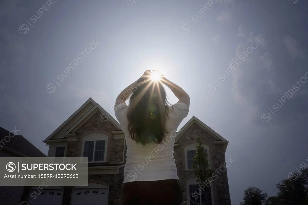 Chinese woman with arms raised looking at sun