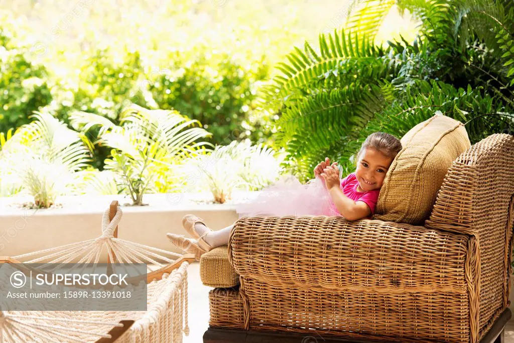Hispanic girl sitting in armchair outdoors