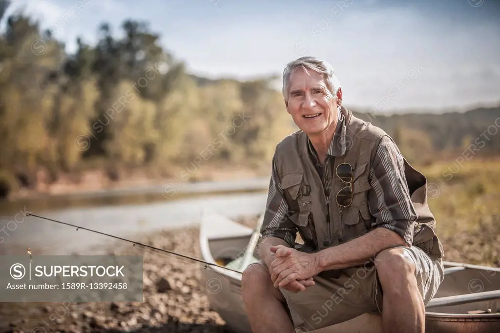 Older Caucasian man holding fishing rod near river