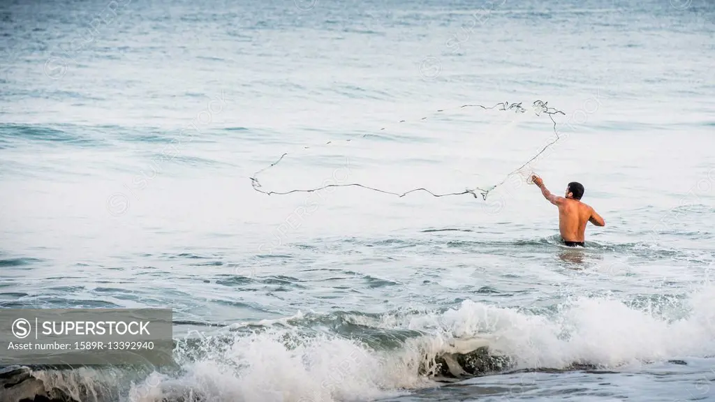 Man throwing fishing net into ocean waves
