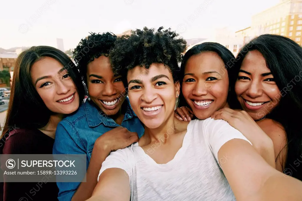Smiling women taking selfie on urban rooftop