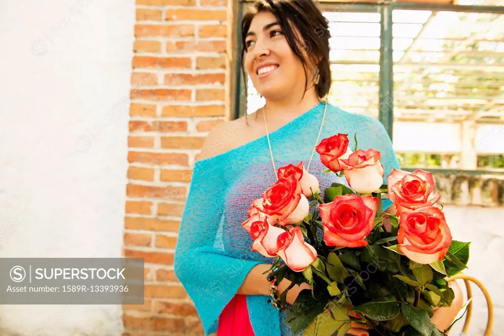 Hispanic woman carrying bouquet of roses outdoors