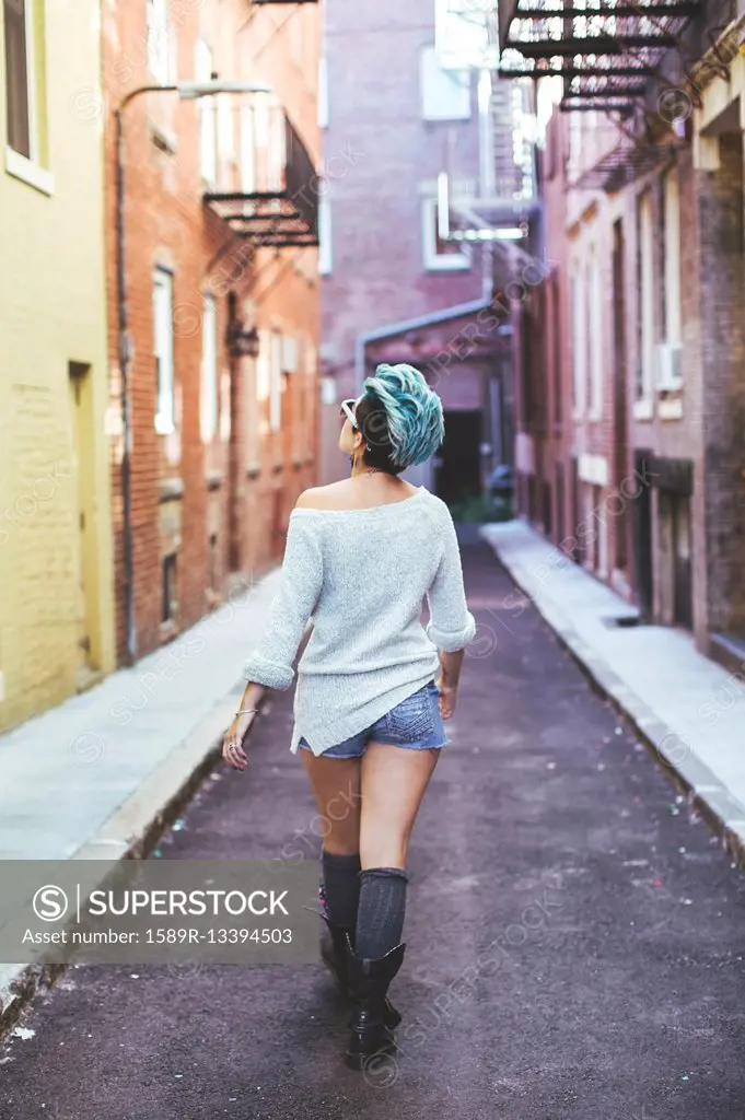 Caucasian woman walking in urban alleyway