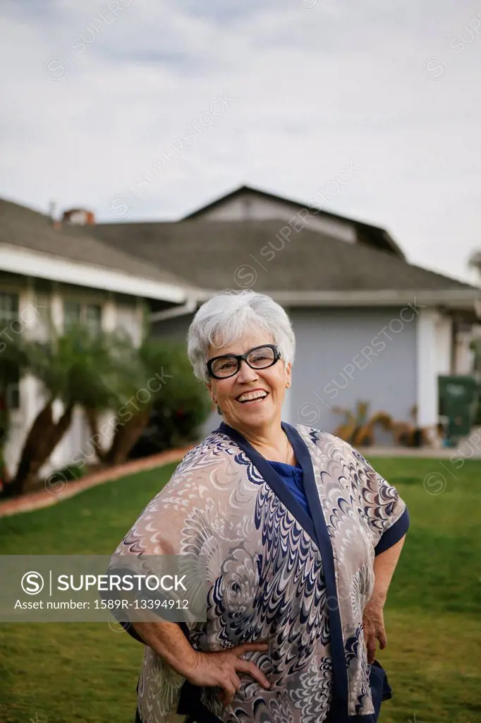 Older woman standing with hands on hips in backyard