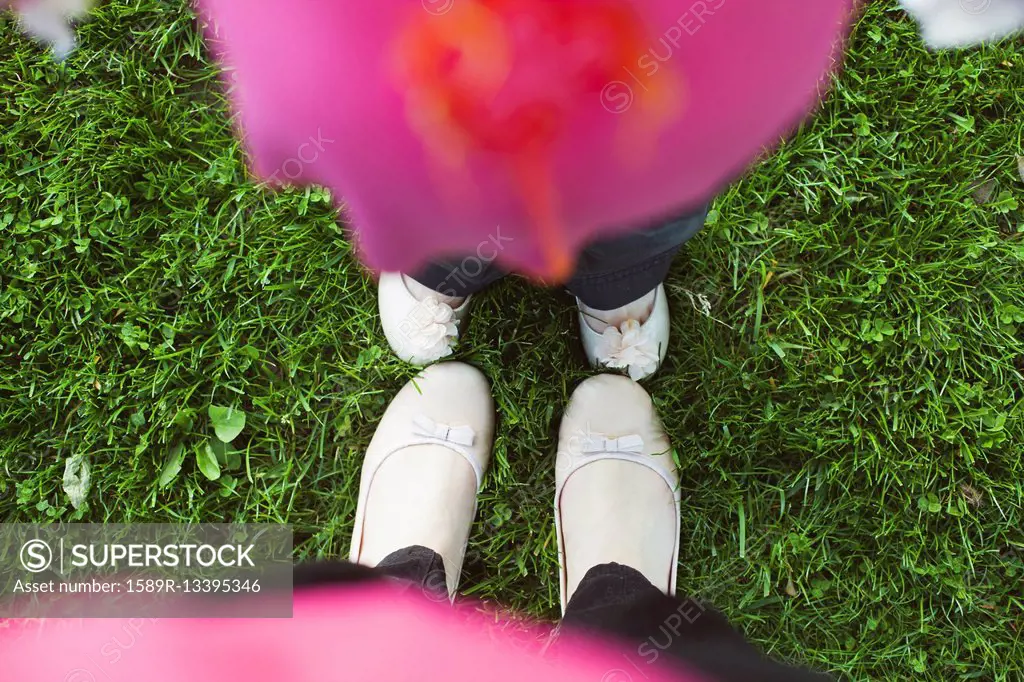 High angle view of feet of mother and daughter in grass