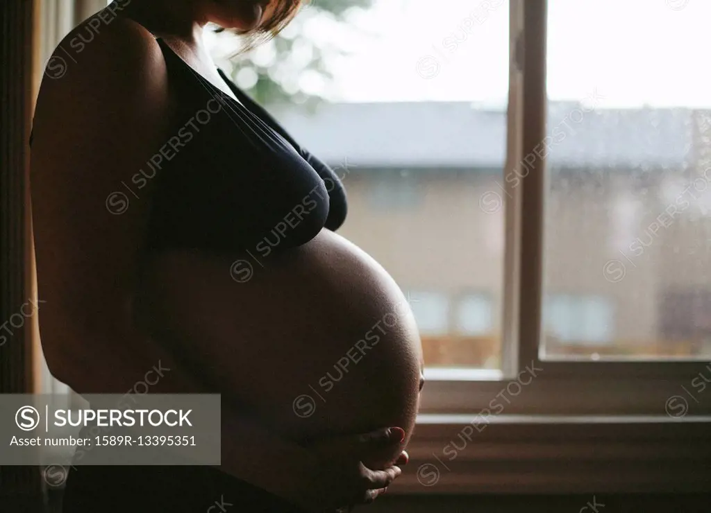 Pregnant Caucasian woman standing at window