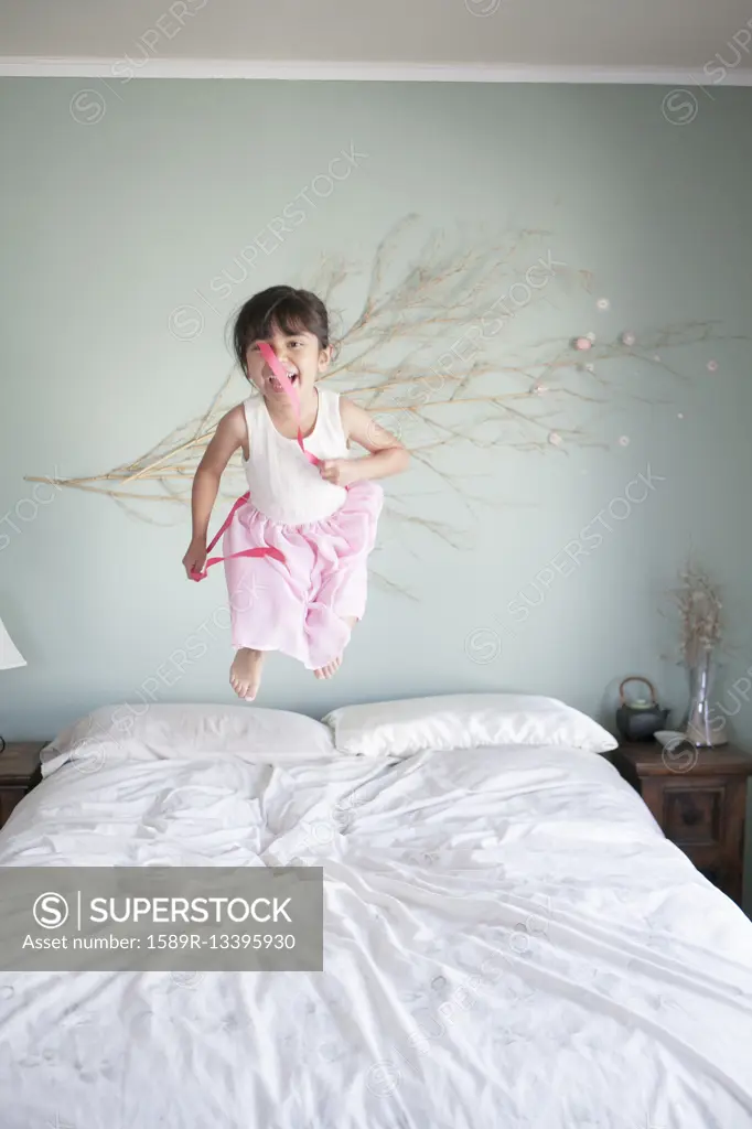 Hispanic girl jumping on bed