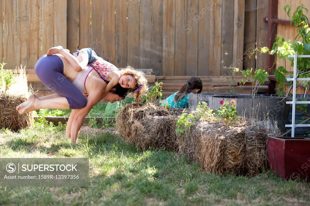 Mother and daughter practicing yoga in backyard