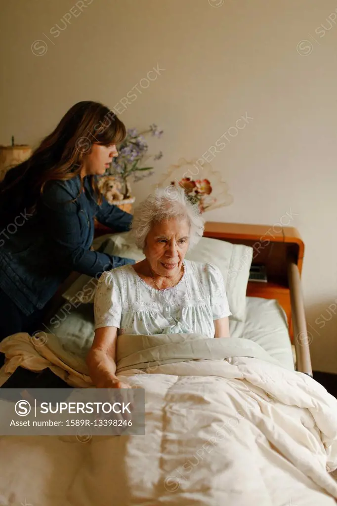 Granddaughter helping grandmother into bed
