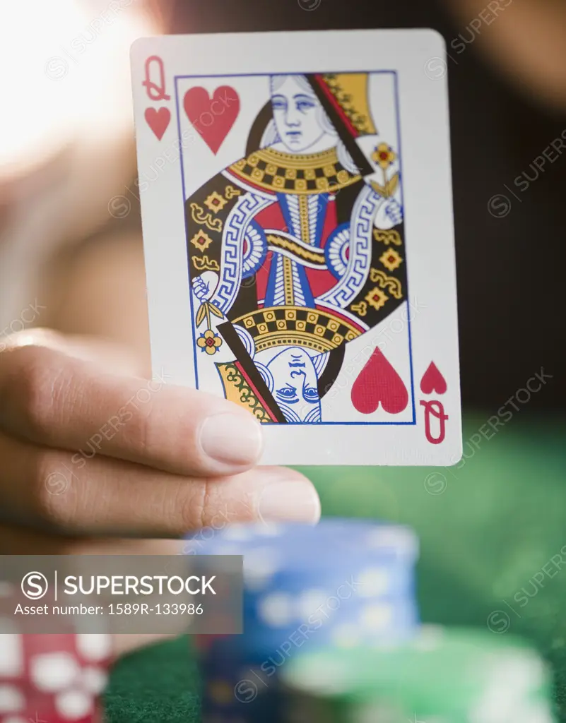 Hand holding queen of hearts playing card