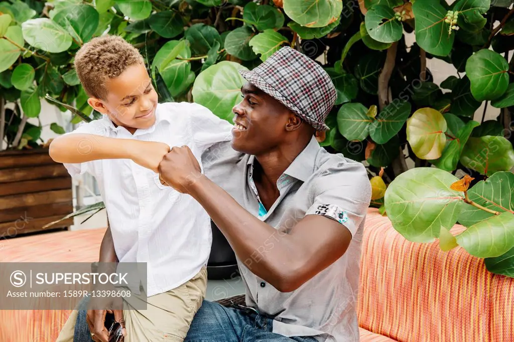 Father and son giving fist bump in backyard