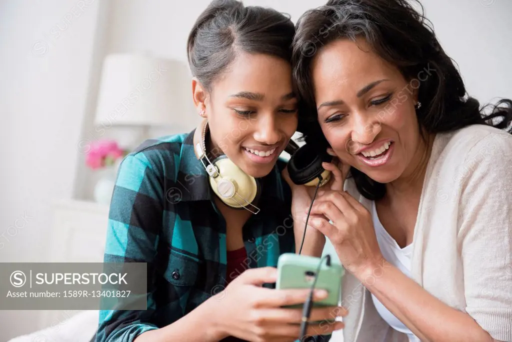 Mother and daughter listening to cell phone music on headphones