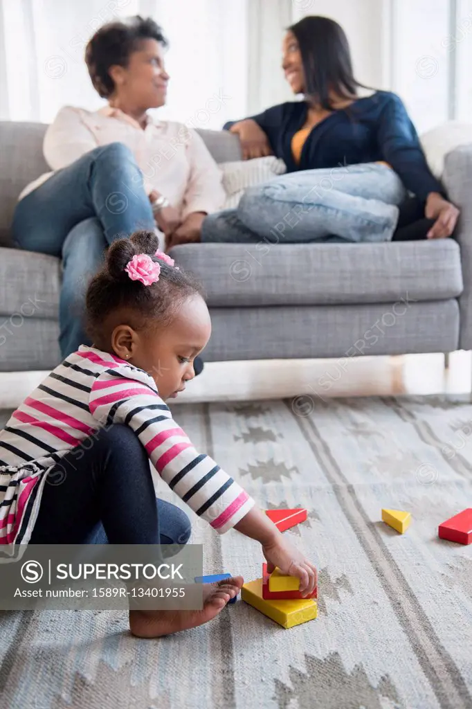 black baby girl playing on carpet with blocks