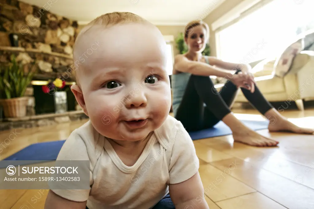 Baby crawling on floor while mother rests from workout