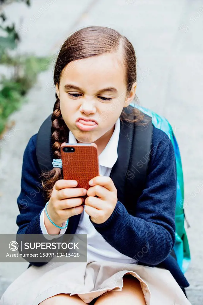 Mixed race girl making a face at cell phone