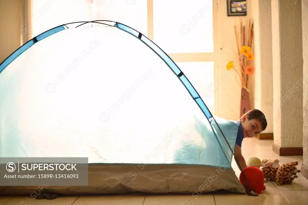 Hispanic boy camping in tent indoors