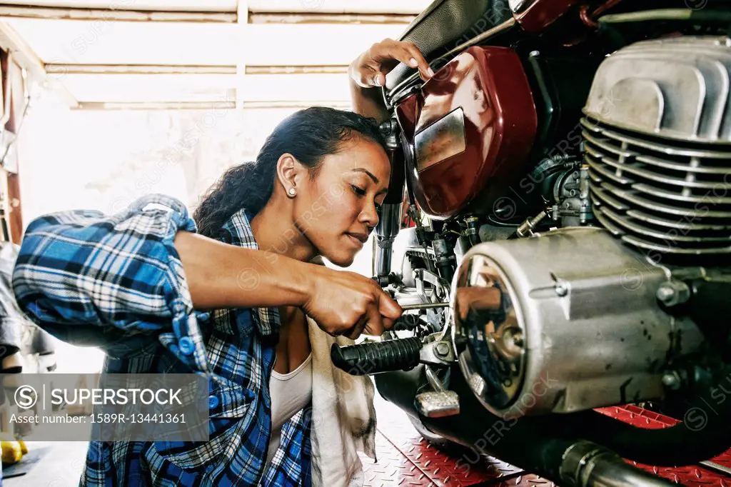 Mixed Race woman repairing motorcycle in garage