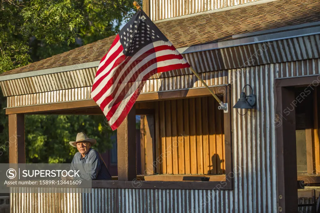 Serious Caucasian farmer on porch with American flag